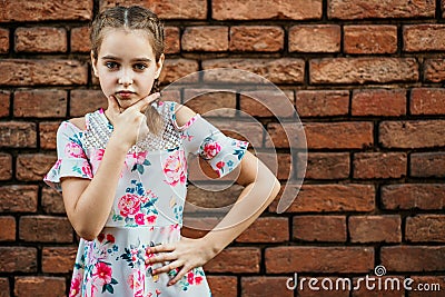 Portrait of a girl against a brick wall, expression of doubt Stock Photo