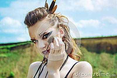 Portrait of a girl with aggressive makeup amazon viking presses prickly flowers thistle to her face Stock Photo