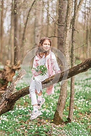 Portrait of a girl with a bouquet of anemone. A child in the spring forest Stock Photo