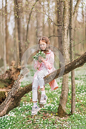 Portrait of a girl with a bouquet of anemone. A child in the spring forest Stock Photo