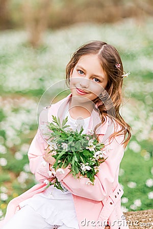 Portrait of a girl with a bouquet of anemone. A child in the spring forest Stock Photo