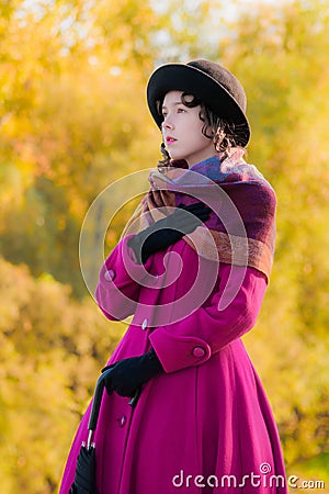 Portrait girl in a bright crimson coat in sunny autumn day outdo Stock Photo