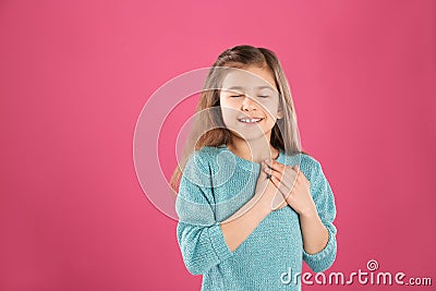 Portrait of girl holding hands near her heart on color background Stock Photo