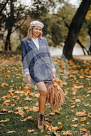 Portrait of a Girl in a jacket and birette with an autumn bouquet in an autumn park Stock Photo