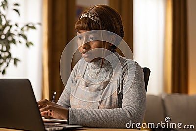 Portrait of a girl looking into a laptop screen. Noting down the most necessary infomercials for next week . Organizing Stock Photo