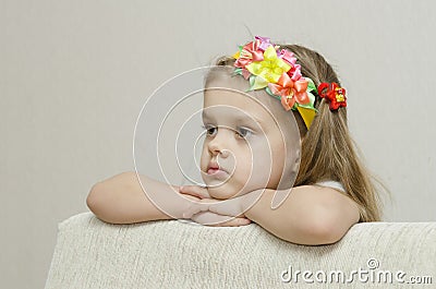 Portrait of a girl that looks thoughtfully left leaning his elbow on the back of the sofa Stock Photo