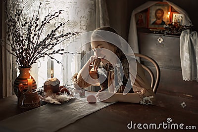Portrait of a girl painting eggs on the background of icons Stock Photo