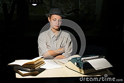 Portrait of a girl sitting at a table with a typewriter and books, think about the idea at night Stock Photo