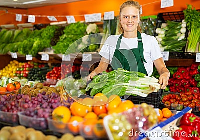 Portrait of a girl working part-time as a trainee seller, holding a crate of precocious Chinese cabbage Stock Photo