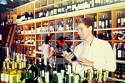 Portrait of glad male customer taking bottle of wine in store Stock Photo