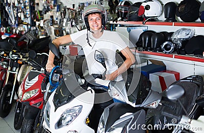 Portrait of glad male in helmet on motorbike in the store Stock Photo
