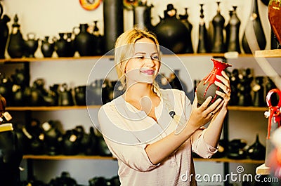 Portrait of glad woman choosing glazed with red color ceramic ut Stock Photo