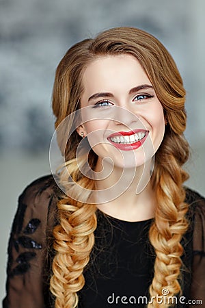 Portrait of a glamorous beautiful girl with bright makeup in black dress and braids, laughing, studio, close-up Stock Photo