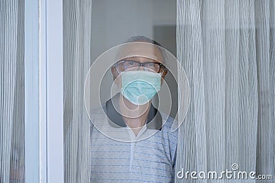Grandfather looking through the window with mask Stock Photo