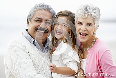 Portrait Of Grandparents On Beach With Granddaughter Stock Photo