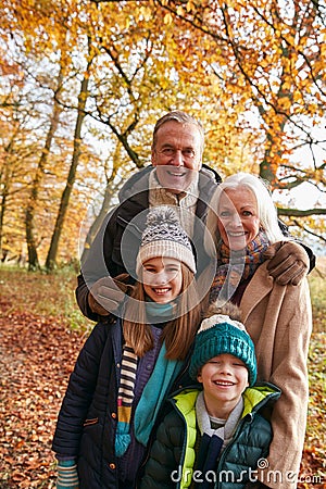 Portrait Of Grandparents With Grandchildren Enjoying Walk Along Autumn Woodland Path Together Stock Photo