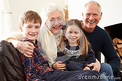 Portrait Of Grandparents Sitting On Sofa With Grandchildren Stock Photo