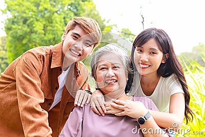 portrait of grandson and granddaughter Take grandma in a wheelchair for a walk in the park. Stock Photo