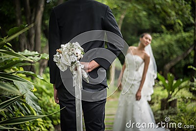 Portrait of a groom hiding a flowers bouquet behind his back to surprise Stock Photo