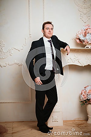 Portrait groom man in black suit on light background Stock Photo