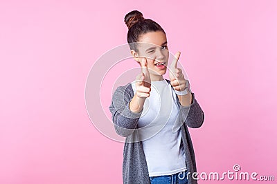 Portrait of groomed brunette teenage girl winking at camera, pointing with finger pistols. isolated on pink background Stock Photo