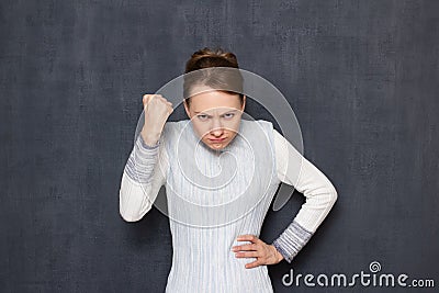 Portrait of grouchy girl shaking fist in threatening gesture Stock Photo