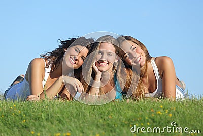 Portrait of a group of three happy teenager girls smiling lying on the grass Stock Photo