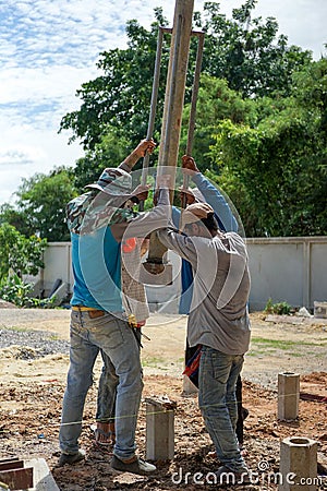 Portrait group of workers hit the concrete piles into the ground by manual steel tools at the construction site Editorial Stock Photo
