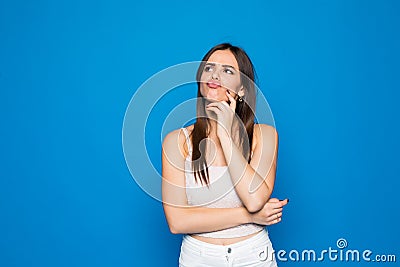 Portrait of grumpy moody girl standing isolated over blue background Stock Photo
