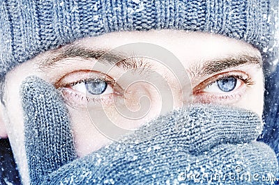 Portrait of a guy with blue eyes against a background of falling snow. Beautiful snowy weather. Snowing. Christmas image Stock Photo