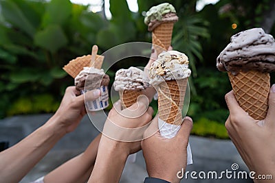 Portrait of hands holding ice cream cone background green trees Stock Photo