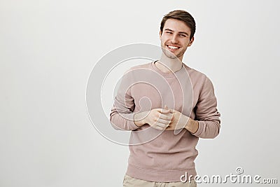 Portrait of handsome athletic male with charming smile holding hands near chest, standing in casual post as if talking Stock Photo