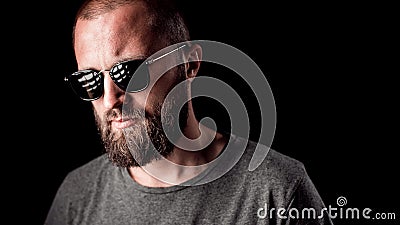 Portrait of a handsome balded man with long well trimmed beard wearing sunglasses and grey shirt Stock Photo