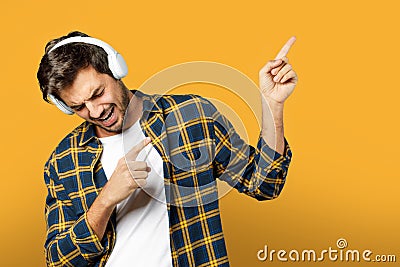 Portrait of handsome beard guy in white t-shirt and plaid shirt listening to music in headphones singing Stock Photo