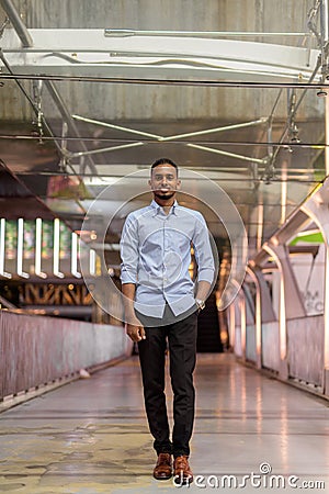 Portrait of handsome black African businessman outdoors in city at night standing at footbridge Stock Photo