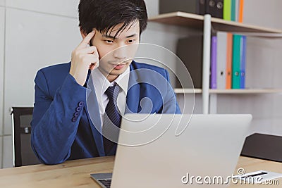 Portrait handsome businessman. Attractive handsome young business man is thinking and working work on laptop computer on desk Stock Photo