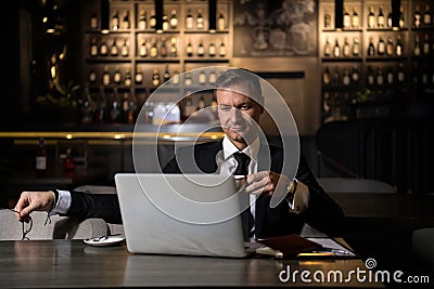 Portrait of handsome elegant caucasian businessman sitting at restaurant working on his laptop and drinking coffee Stock Photo