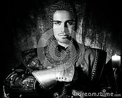 Portrait of handsome knight in suit of armour looking at camera with candles in background Stock Photo