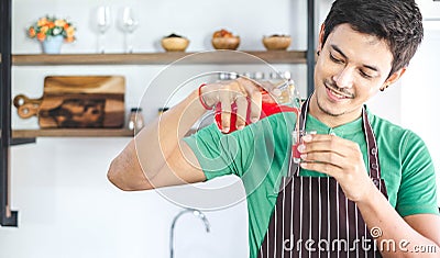 A portrait of handsome man making cold presses fruit juice in a modern kitchen. Stock Photo