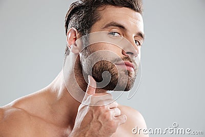 Portrait of a handsome naked bearded man examining his face Stock Photo