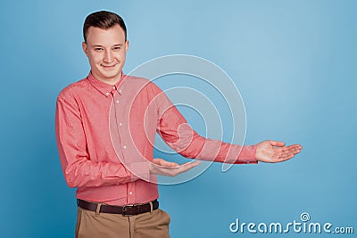 Portrait of handsome reliable guy hands displaying blank space on blue background Stock Photo
