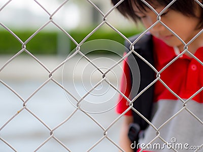 Portrait of handsome sad boy behind fence mesh netting. Stock Photo
