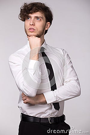 Portrait of handsome serious pensive man in white shirt, looking upwards thinking about problem, holding his chin. Stock Photo