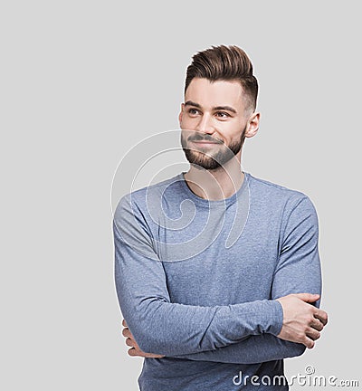 Portrait of handsome smiling young man with folded arms isolated on gray background. Joyful cheerful men with crossed hands Stock Photo