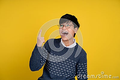Portrait of a handsome tomboy looking good. Asian woman with short hair on yellow background. She is shocked, gasps and pointing Stock Photo
