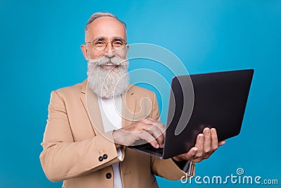 Portrait of handsome trendy elderly retired cheery pensioner grey-haired man typing text isolated over bright blue color Stock Photo