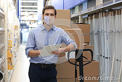 Portrait of handsome warehouse wears medical mask during epidemy. Worker in a cash and carry wholesale store Stock Photo