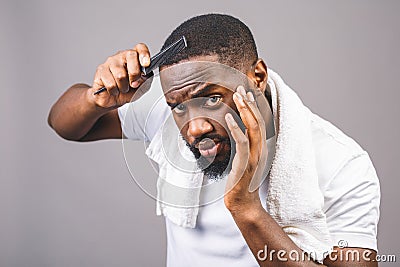 Portrait of handsome young african american black man combing his hair in bathroom. Isolated over grey background Stock Photo