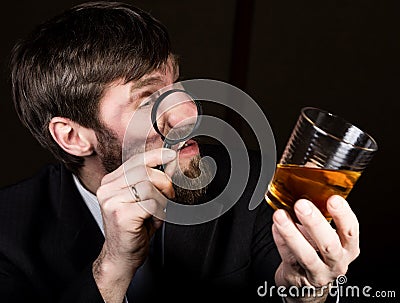 Portrait of handsome young businessman looking at brandy through magnifying glass Stock Photo