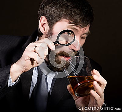 Portrait of handsome young businessman looking at brandy through magnifying glass Stock Photo